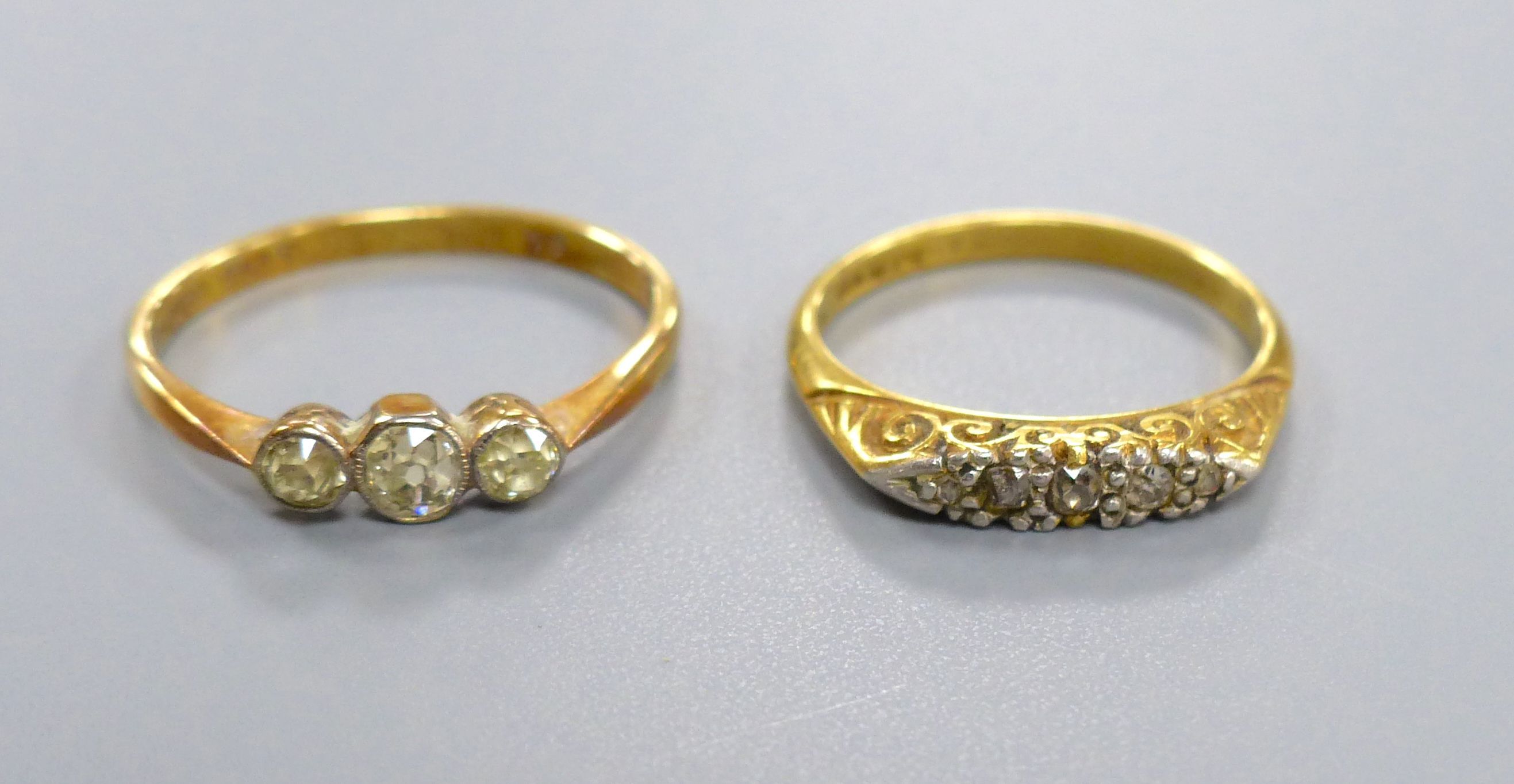 An 18ct gold three-stone diamond ring and another similar ring, gross 5.2 grams.